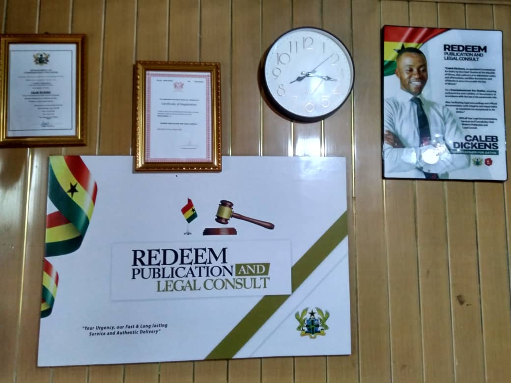 Wall of the Redeem main office showing the framed appointment and registration certificates, the business signboard and a framed portrait of Caleb Dickens